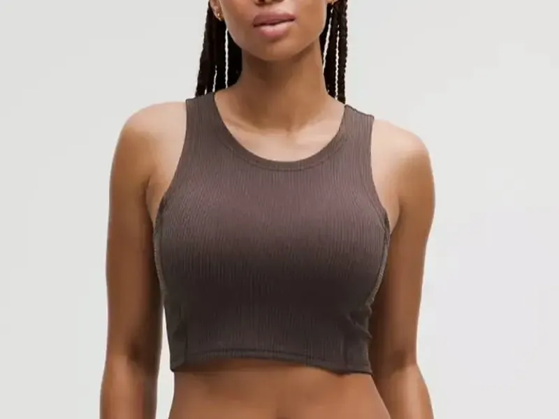 Model wearing a fitted brown training crop top against a plain studio backdrop
