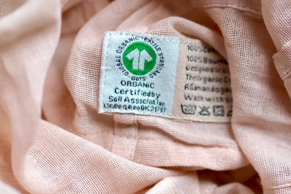 A pale pink organic cotton garment with a sewn-in GOTS certification label