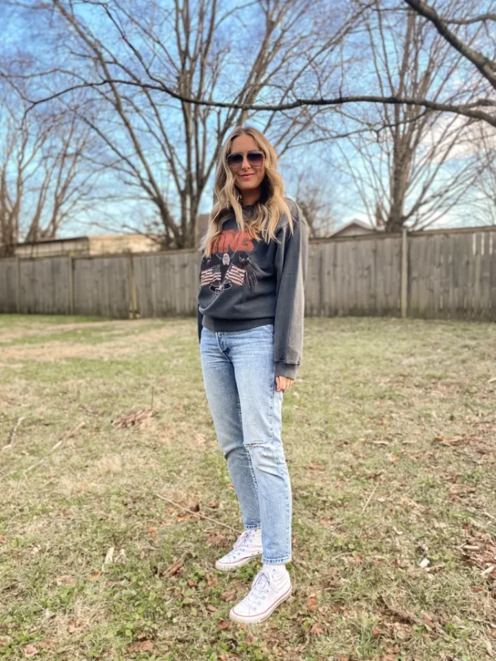 A customer in a grey graphic sweatshirt, jeans and sunglasses, standing in a back garden
