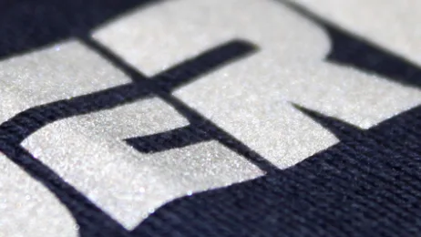 A close-up of a silver reflective transfer print on navy fabric