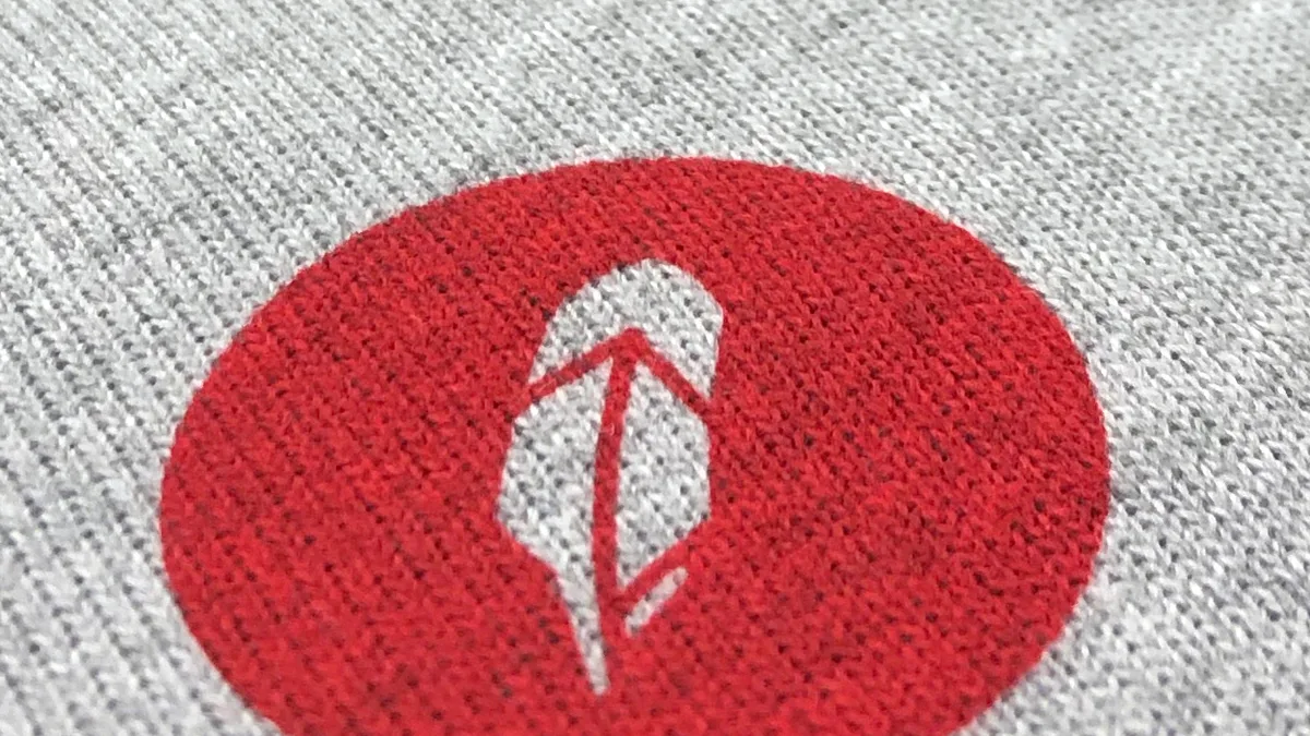 A soft red water-based print of a feather logo on grey melange knit