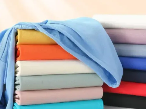 Folded sweatshirt fabrics stacked in blue, orange, cream, sage and pink
