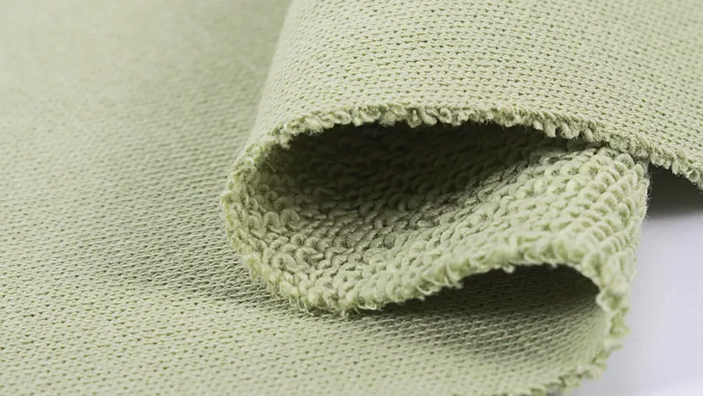 Close-up of pale green heavyweight loop-back terry, folded to show the thick loops