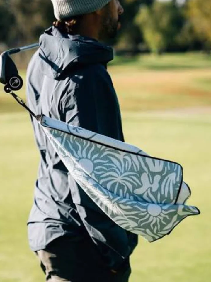 Hanging from a bag strap on the course, a blue and white printed golf towel