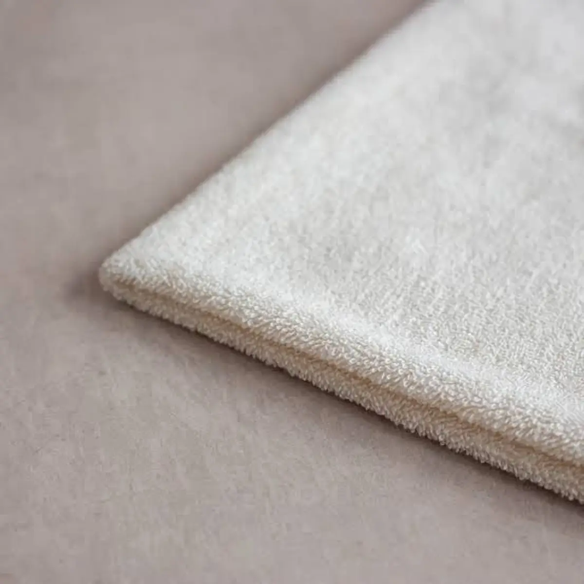 Ivory cotton terry seen close up, a folded corner catching the light