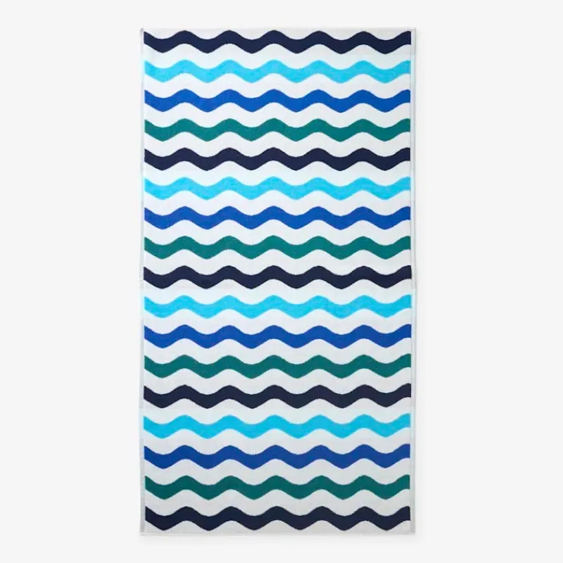 Blue and teal wavy stripes printed across a white beach towel, laid flat