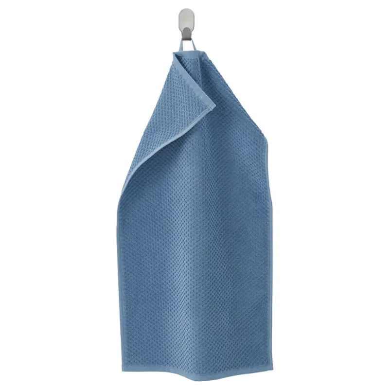 Waffle-weave hand towel in blue, hanging from a hook and folded into a triangle