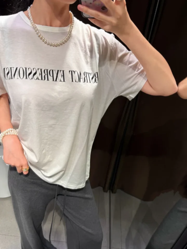 A customer in a relaxed white slogan t-shirt, photographed in a mirror