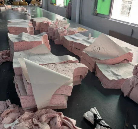 Stacks of freshly cut fabric panels with paper patterns on a cutting table