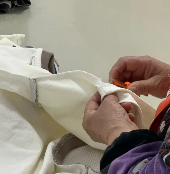 A worker checking the neckline stitching of a t-shirt on the production floor